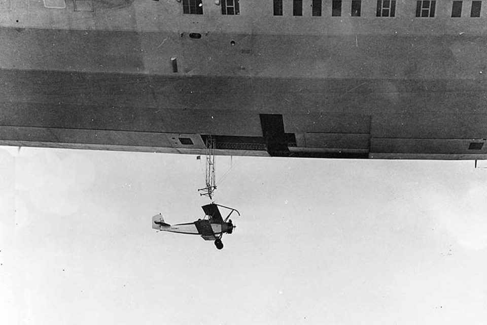 Um biplano de treinamento Consolidated N2Y prestes a engatar no "trapézio" do USS Akron