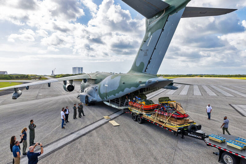 O KC-390 na famosa pista do ônibus espacial e ao fundo as estruturas para lançamento de foguetes